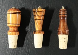 Three wine corks topped with a turned wooden spool to grip.
