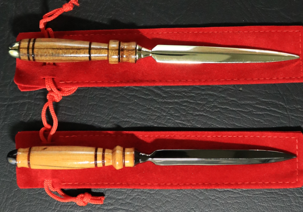 Two metal-bladed letter openers with dark-banded wooden handles. One has gold-tone metal accents and the other has black-toned metal.