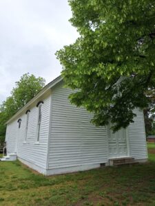 A rectangular white building with black trim along the top of the side windows.